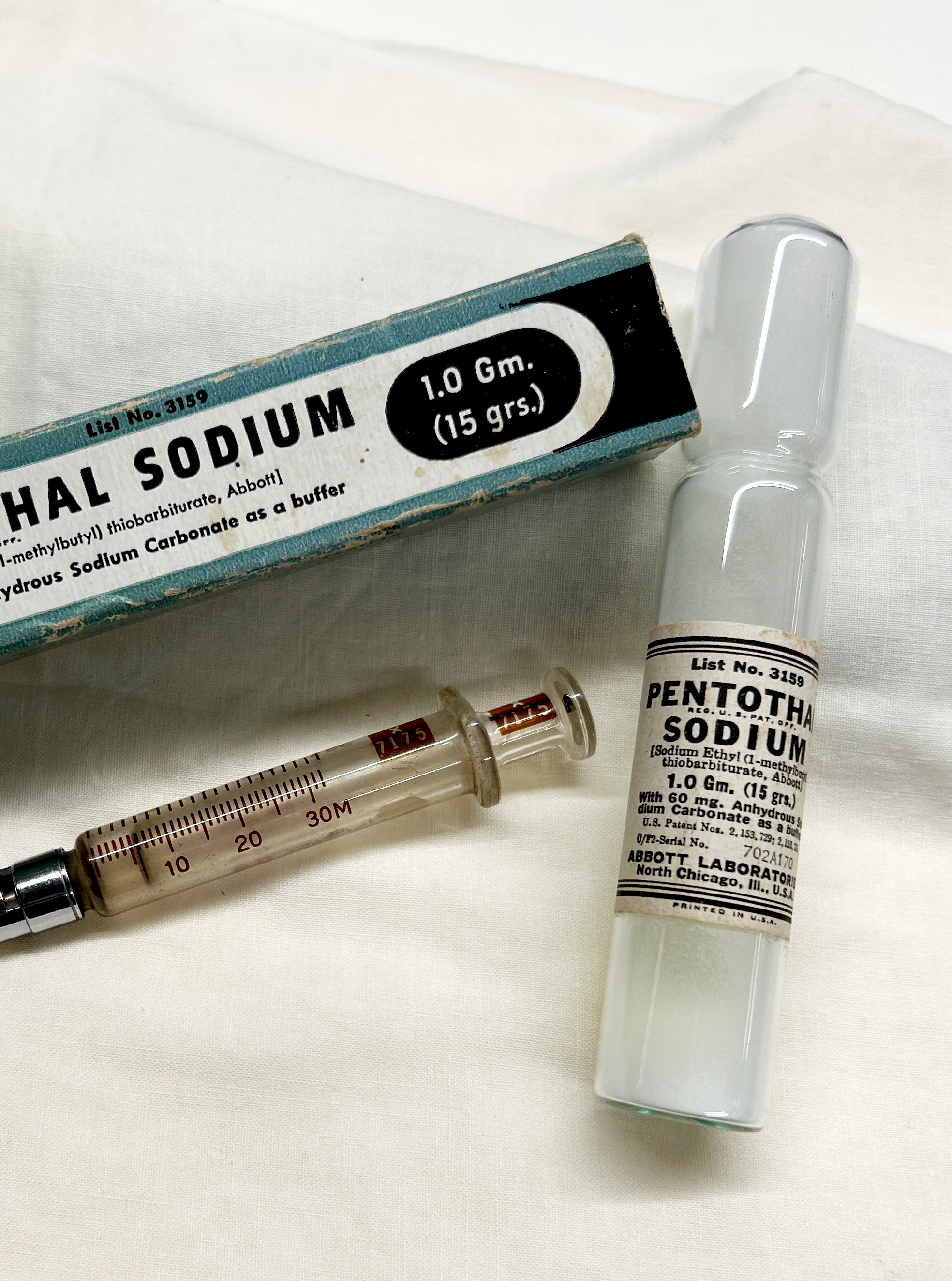 Glass vial with powder next to a syringe and cardboard box